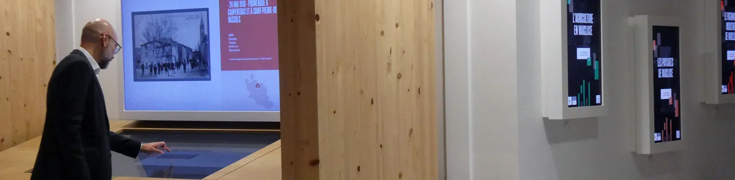 Un homme manipule avec le doigt les informations de l'écran horizontal de la table numérique