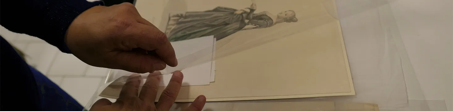 Des mains d'homme mettent sous film plastique une gravure