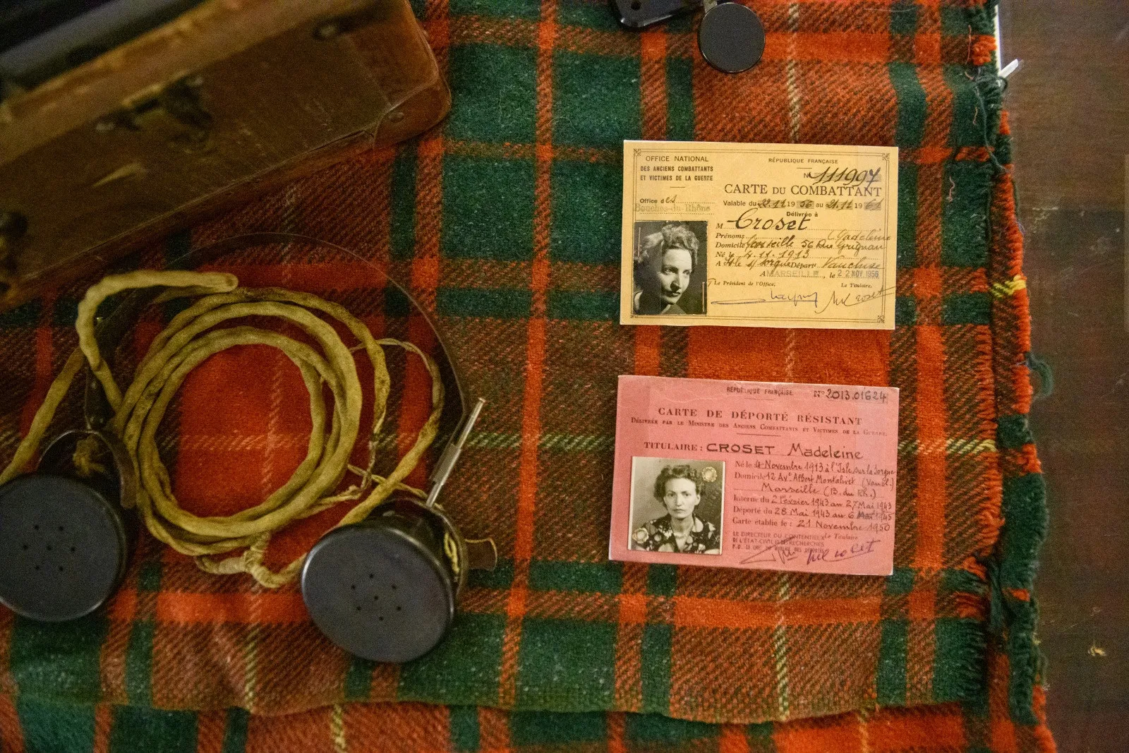 Carte rose et carte saumon posées sur une couverture aux motifs écossais ; à gauche de l'image, des écouteurs datant de la 2nde Guerre mondiale