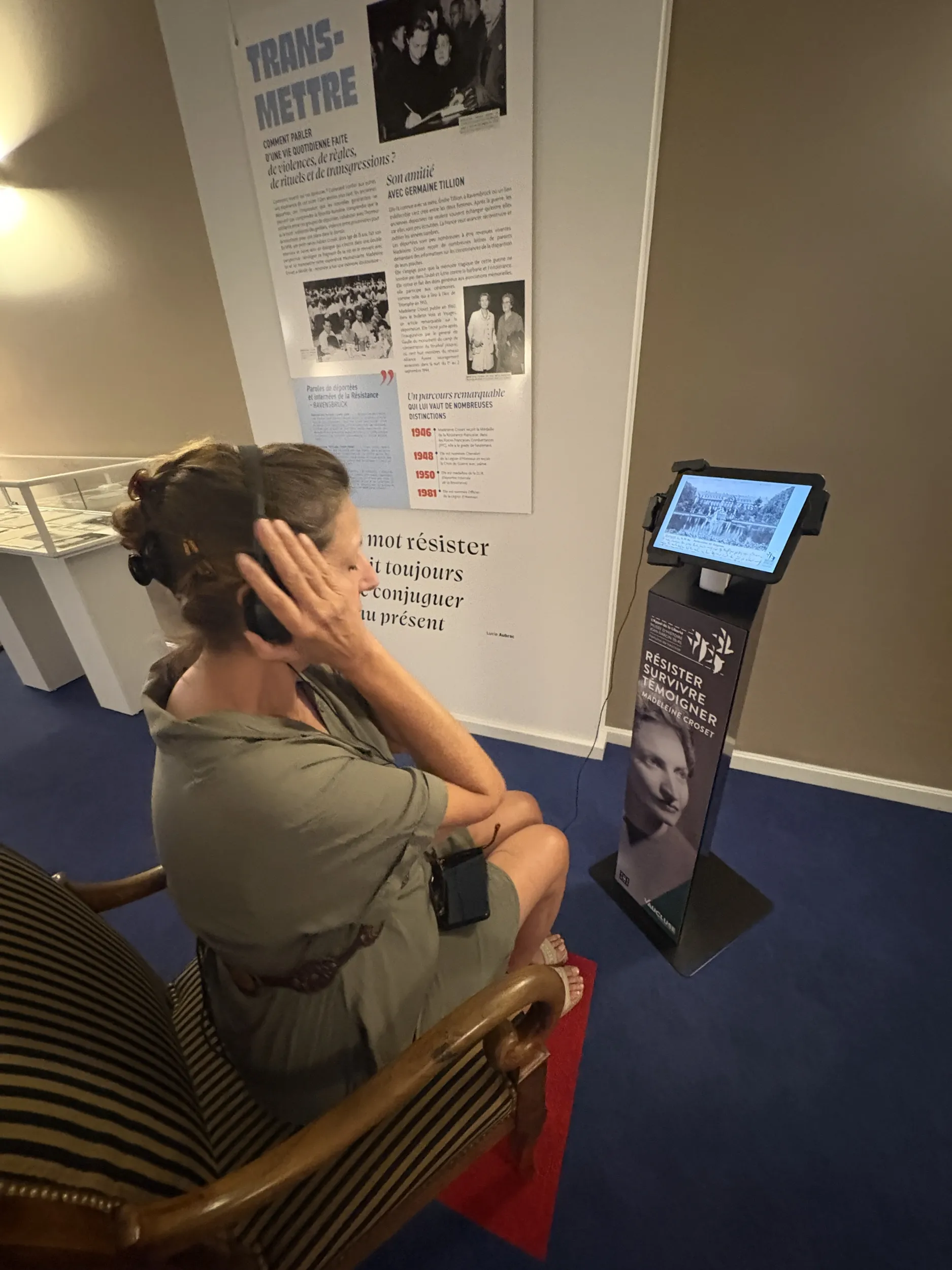 Une visiteuse de dos, assise sur un fauteuil, porte un casque sur les oreilles