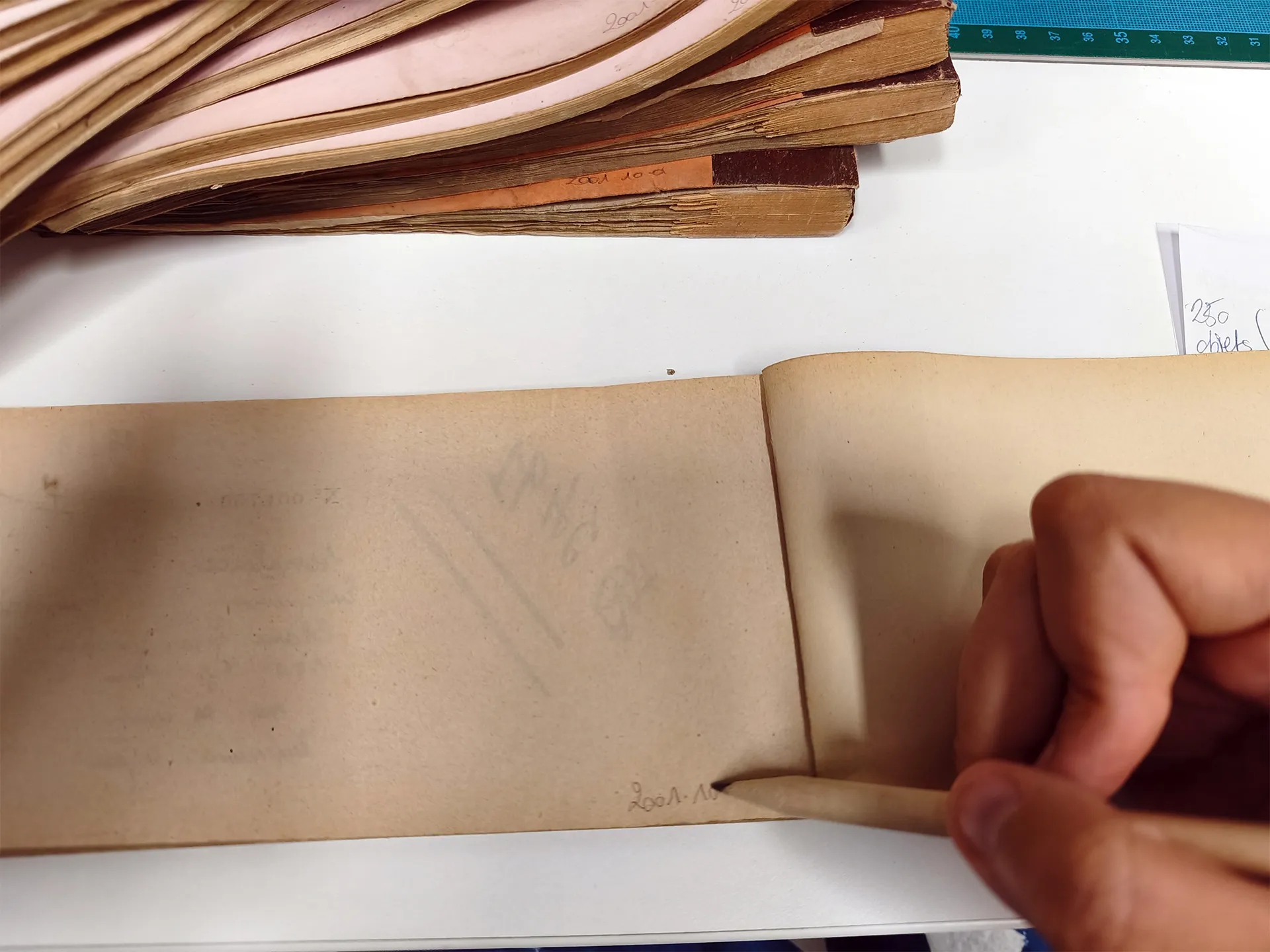 Une main tient un crayon posé sur un carnet