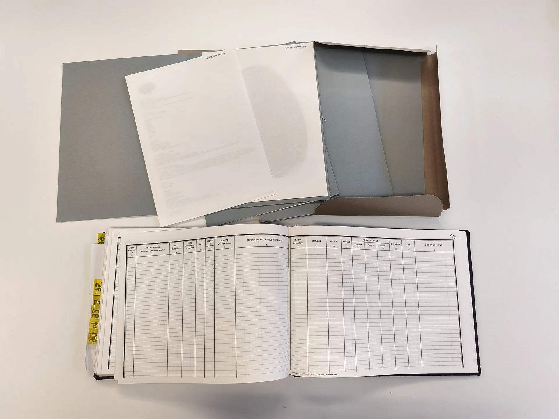 Boîte grise en carton ouverte et registre ouvert sur double-page vierge