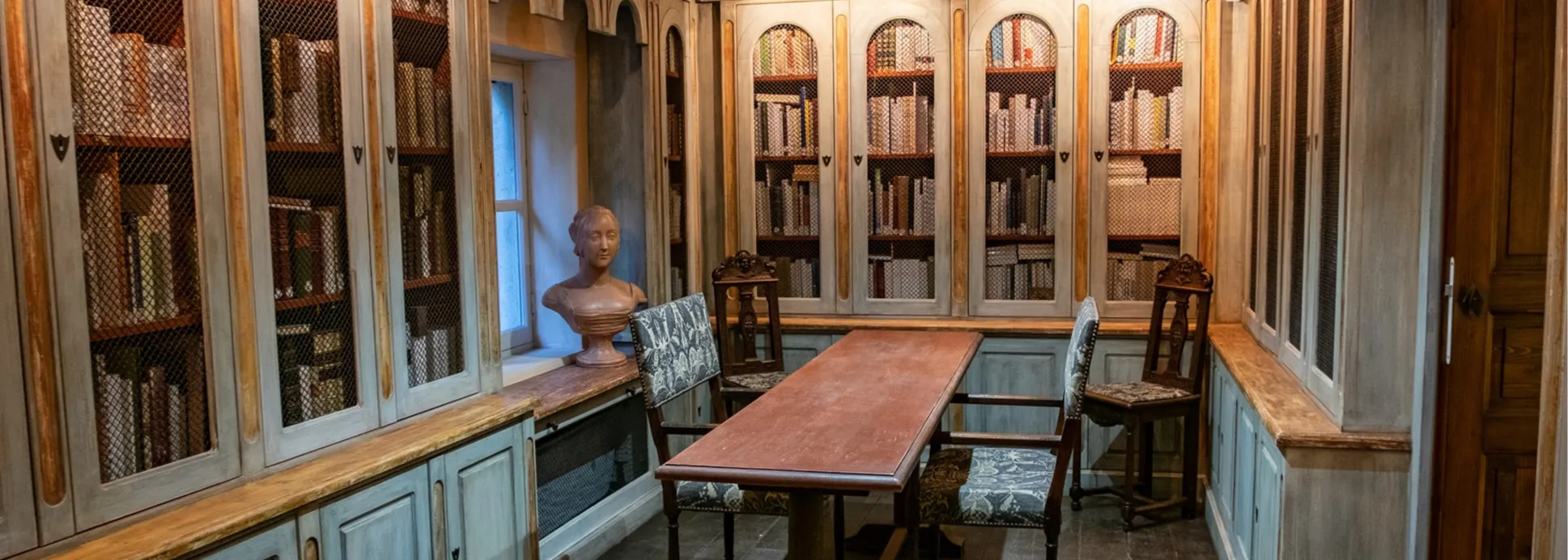 Vue de la bibliothèque du musée bibliothèqe François Pétrarque : buste de Laure de Noves, table et fauteuils de consultation