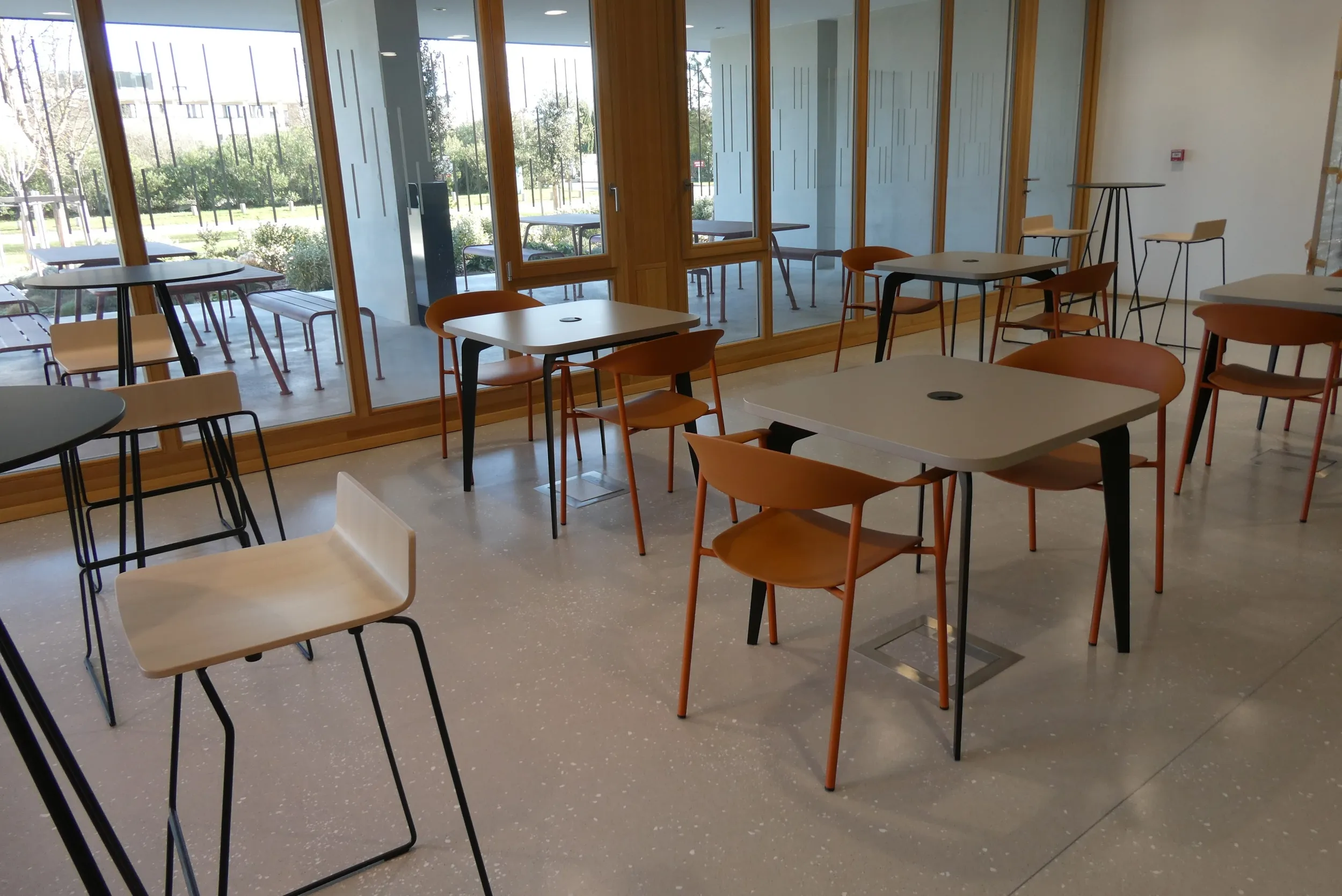 Tables et chaises métalliques dans un espace vitré lumineux