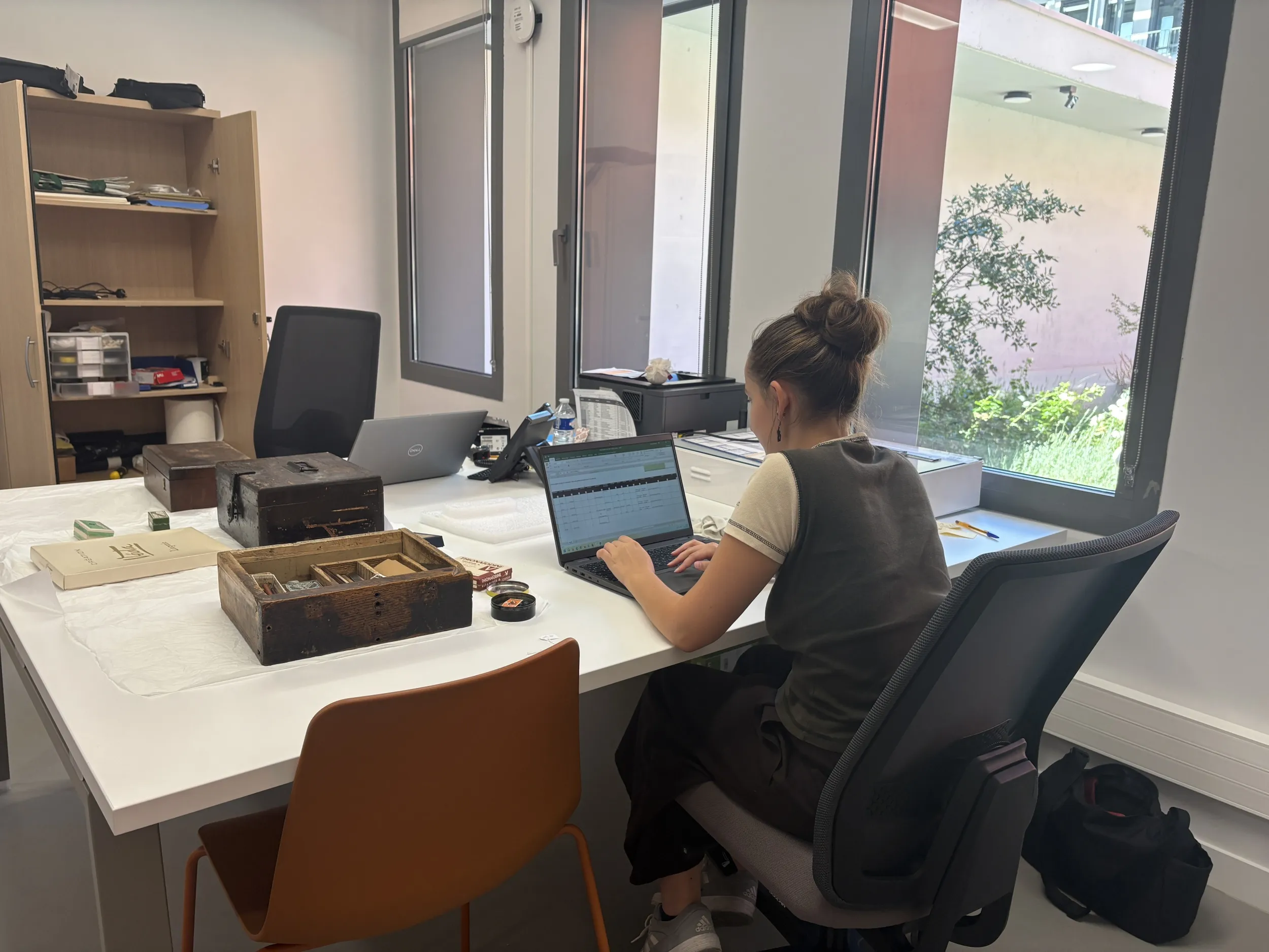 Jeune fille de dos travaillant à son ordinateur devant un bureau