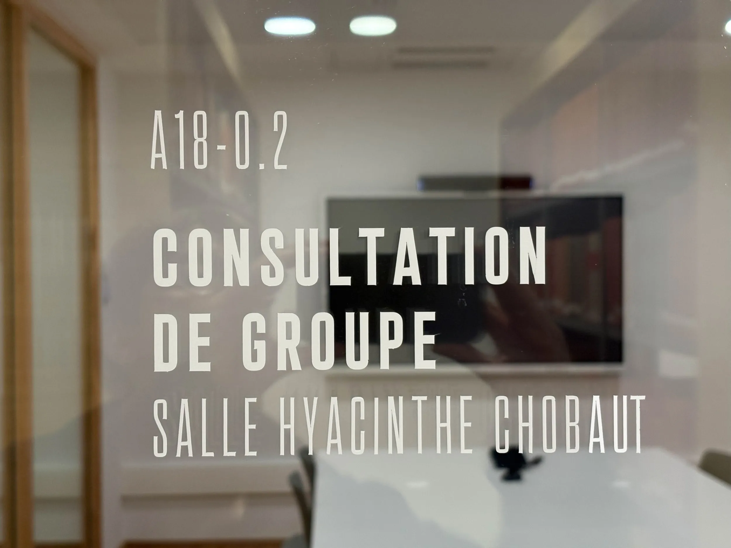 Baie vitrée portant la signalétique "Consultation de groupe, salle Hyacinthe Chobaut"