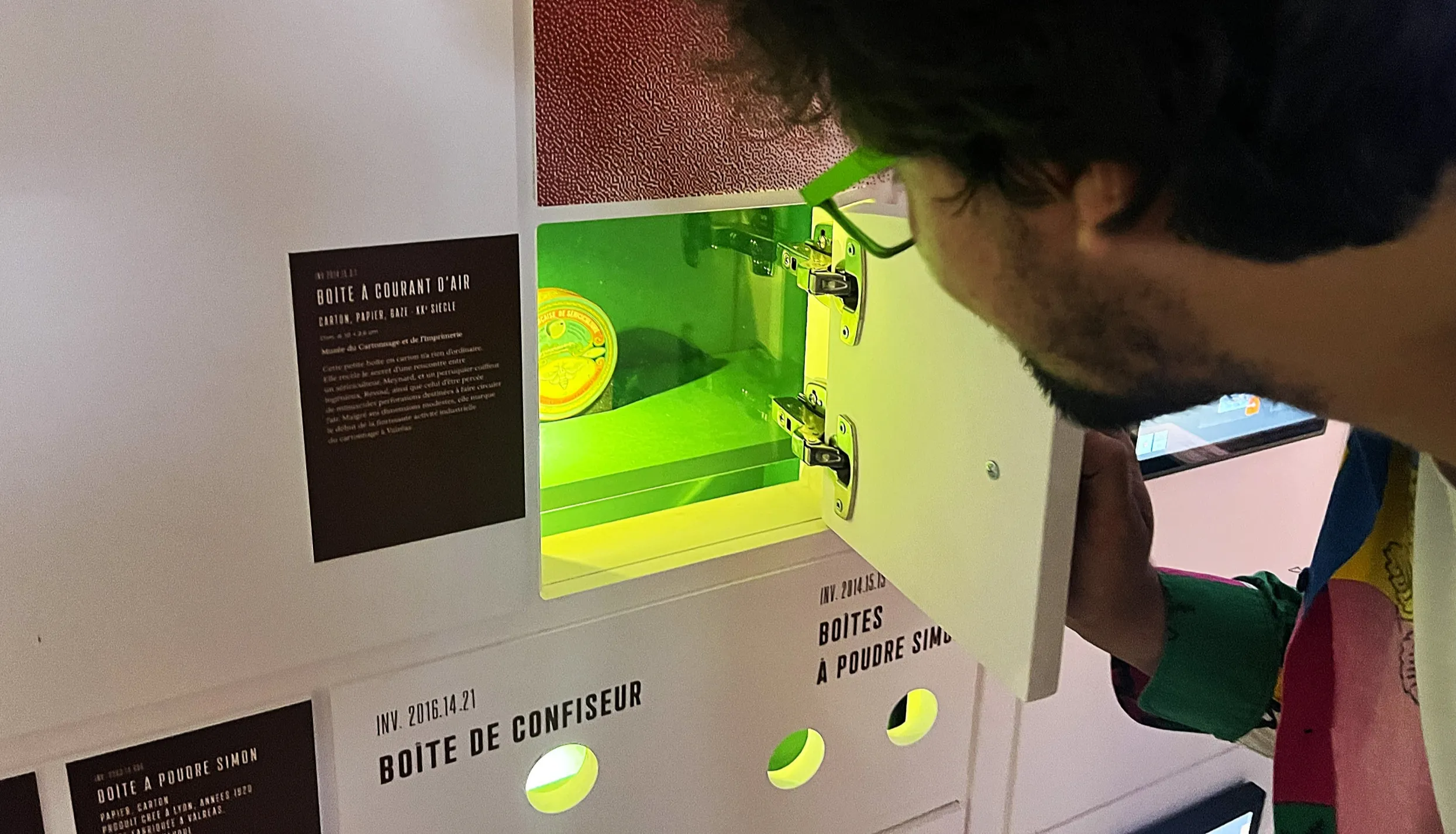 Un visiteur ouvre la porte d'une niche dans laquelle figure un objet éclairé