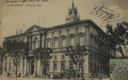 Vue d'un grand bâtiment XIXe, façade à colonnades, tympan équipé d'une horloge, toiture surmontée d'un beffroi